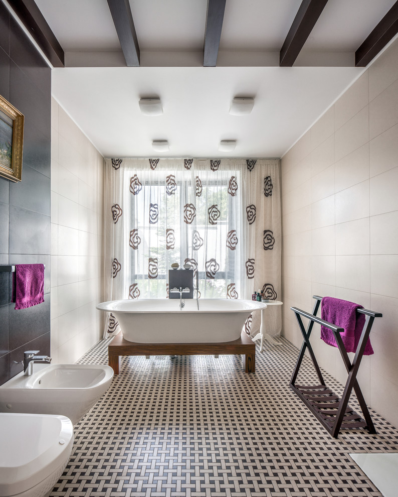 Exemple d'une grande salle de bain principale tendance avec une baignoire sur pieds, un carrelage beige, des carreaux de céramique, un mur beige, un sol en carrelage de porcelaine et un bidet.