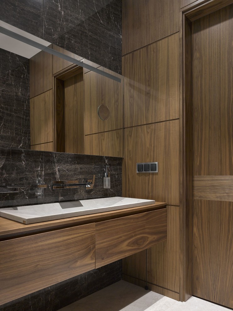 Exemple d'une salle de bain tendance en bois brun de taille moyenne avec un placard à porte plane, un carrelage gris, des carreaux de porcelaine, un sol en marbre, un plan de toilette en bois, une grande vasque et un plan de toilette marron.