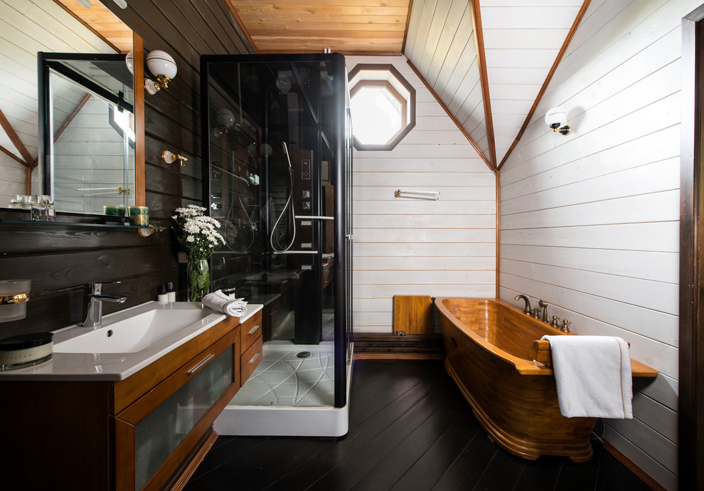 Diseño de cuarto de baño rústico con bañera exenta, paredes blancas, suelo de madera oscura, lavabo integrado y suelo negro