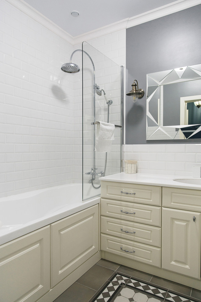 Идея дизайна: ванная комната в стиле неоклассика (современная классика) с фасадами с выступающей филенкой, бежевыми фасадами, ванной в нише, душем над ванной, белой плиткой, серыми стенами, врезной раковиной, белой столешницей, плиткой кабанчик, душевой кабиной, разноцветным полом и открытым душем