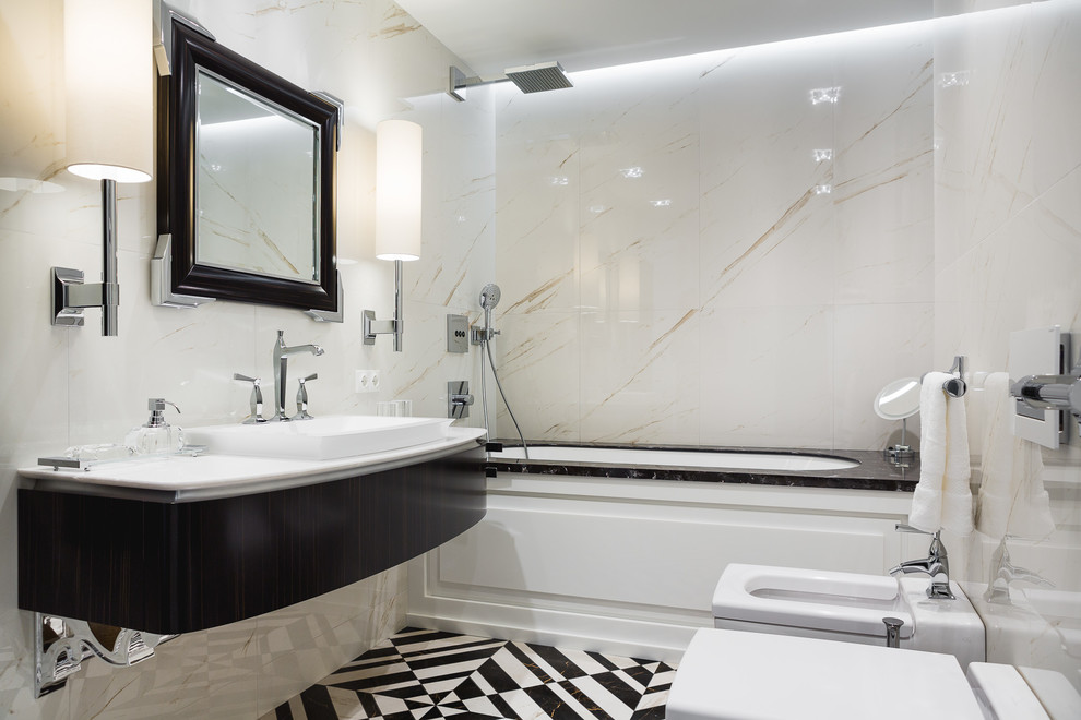 Modern inredning av ett en-suite badrum, med skåp i mörkt trä, ett undermonterat badkar, en bidé, vit kakel, ett nedsänkt handfat och flerfärgat golv