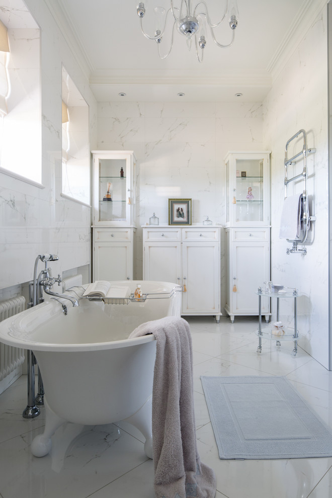 Cette photo montre une salle de bain principale chic avec des portes de placard blanches, une baignoire sur pieds et un carrelage blanc.