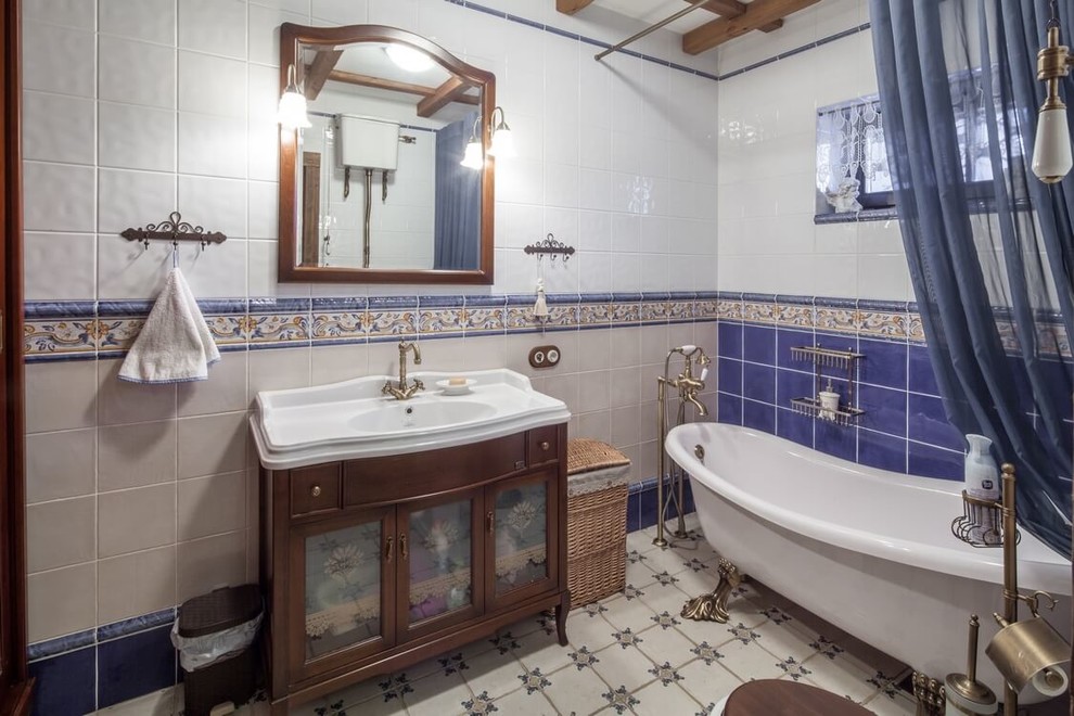 Источник вдохновения для домашнего уюта: главная ванная комната в стиле кантри с ванной на ножках, раздельным унитазом, синей плиткой, белой плиткой, монолитной раковиной и шторкой для ванной