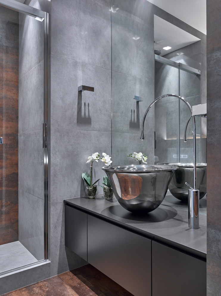 Idée de décoration pour une salle de bain design avec une vasque, un placard à porte plane, des portes de placard grises, un carrelage gris et un mur gris.