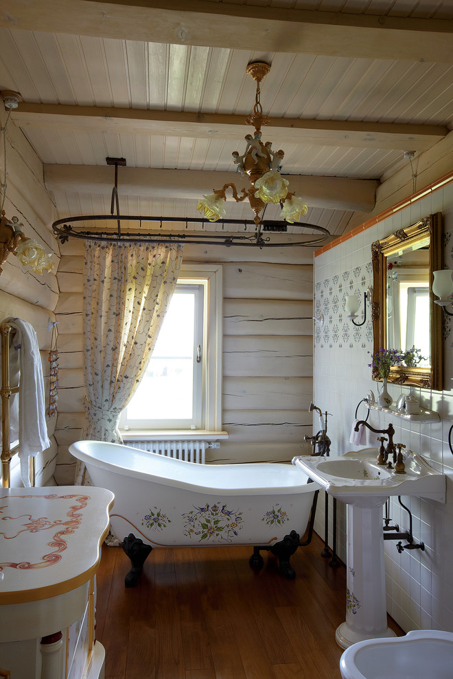 Idéer för mellanstora shabby chic-inspirerade badrum, med ett badkar med tassar, mellanmörkt trägolv, ett piedestal handfat, vita väggar och dusch med duschdraperi