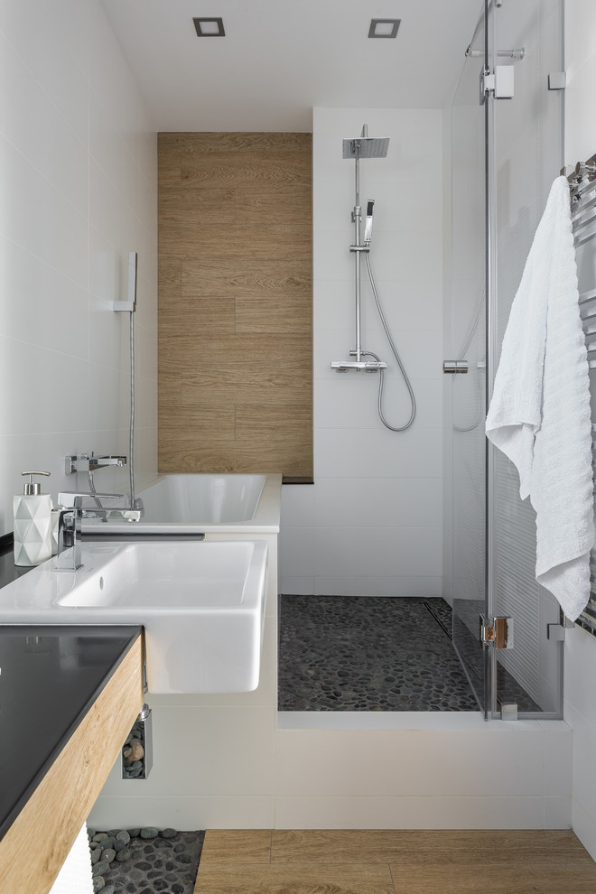 Идея дизайна: ванная комната в современном стиле с ванной в нише, душем над ванной, инсталляцией, черно-белой плиткой, галечной плиткой, белыми стенами, полом из керамогранита, душевой кабиной, консольной раковиной и душем с распашными дверями
