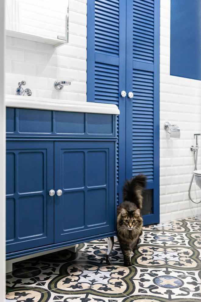Foto på ett mellanstort vintage en-suite badrum, med blå skåp, ett hörnbadkar, vit kakel, blå väggar, klinkergolv i porslin, flerfärgat golv, luckor med infälld panel och tunnelbanekakel