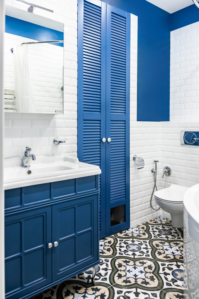 Cette photo montre une salle de bain principale chic de taille moyenne avec un placard à porte persienne, des portes de placard bleues, une baignoire d'angle, un combiné douche/baignoire, WC suspendus, un carrelage blanc, des carreaux de céramique, un mur bleu, un sol en carrelage de porcelaine, un sol multicolore et une cabine de douche avec un rideau.