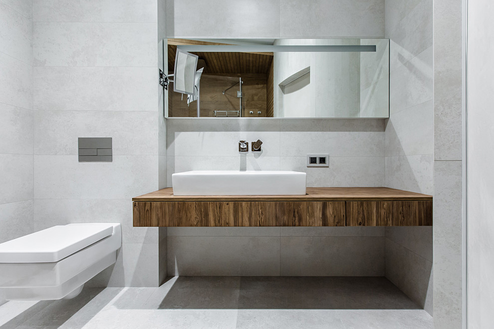 Modernes Badezimmer mit Wandtoilette, grauen Fliesen, Aufsatzwaschbecken und grauem Boden in Sonstige