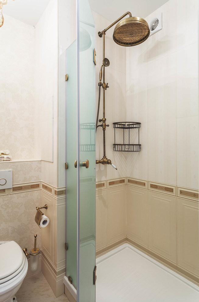 Klassisk inredning av ett badrum med dusch, med en dusch i en alkov, en toalettstol med separat cisternkåpa, beige kakel, beige väggar och dusch med gångjärnsdörr