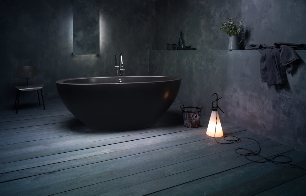 Cette image montre une grande salle de bain principale design avec une baignoire indépendante, un mur gris et un sol en bois brun.
