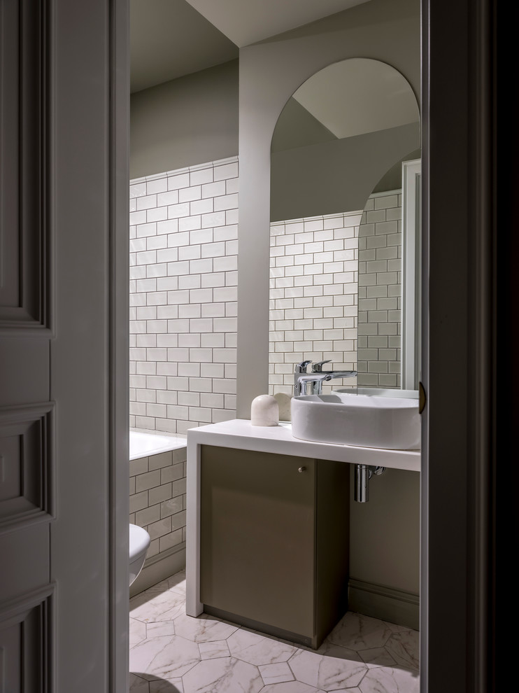 Modelo de cuarto de baño principal actual con bañera empotrada, baldosas y/o azulejos blancos, paredes grises, lavabo sobreencimera y encimeras blancas