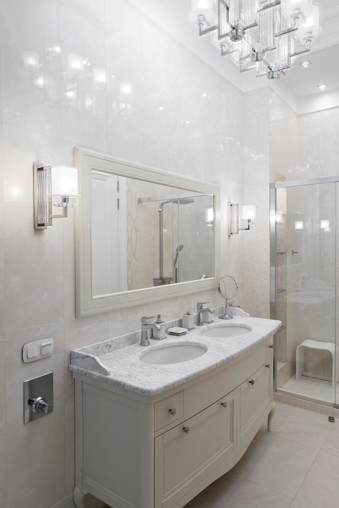 Пример оригинального дизайна: ванная комната среднего размера в стиле неоклассика (современная классика) с фасадами с утопленной филенкой, бежевыми фасадами, белой плиткой, керамогранитной плиткой, белыми стенами, полом из керамогранита, душевой кабиной, мраморной столешницей, бежевым полом и белой столешницей