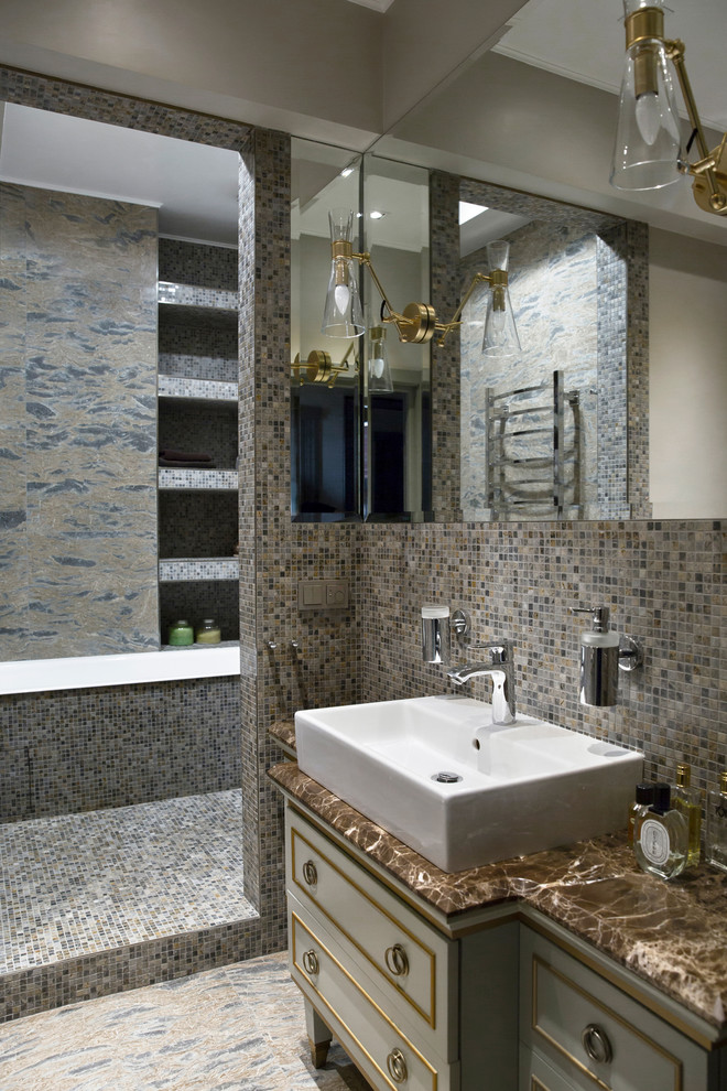 На фото: главная ванная комната в классическом стиле с серыми фасадами, ванной в нише, серой плиткой, плиткой мозаикой, настольной раковиной и мраморной столешницей с