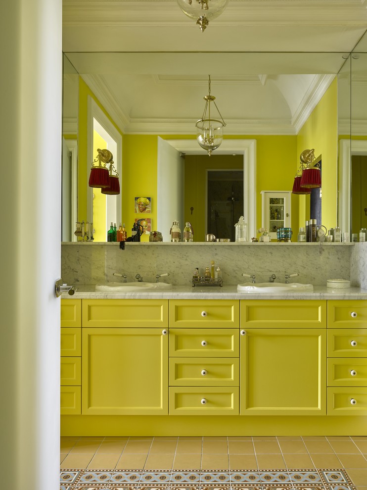 Cette image montre une salle de bain principale bohème avec un placard avec porte à panneau encastré, des portes de placard jaunes, un mur jaune, un sol en carrelage de céramique et un lavabo posé.