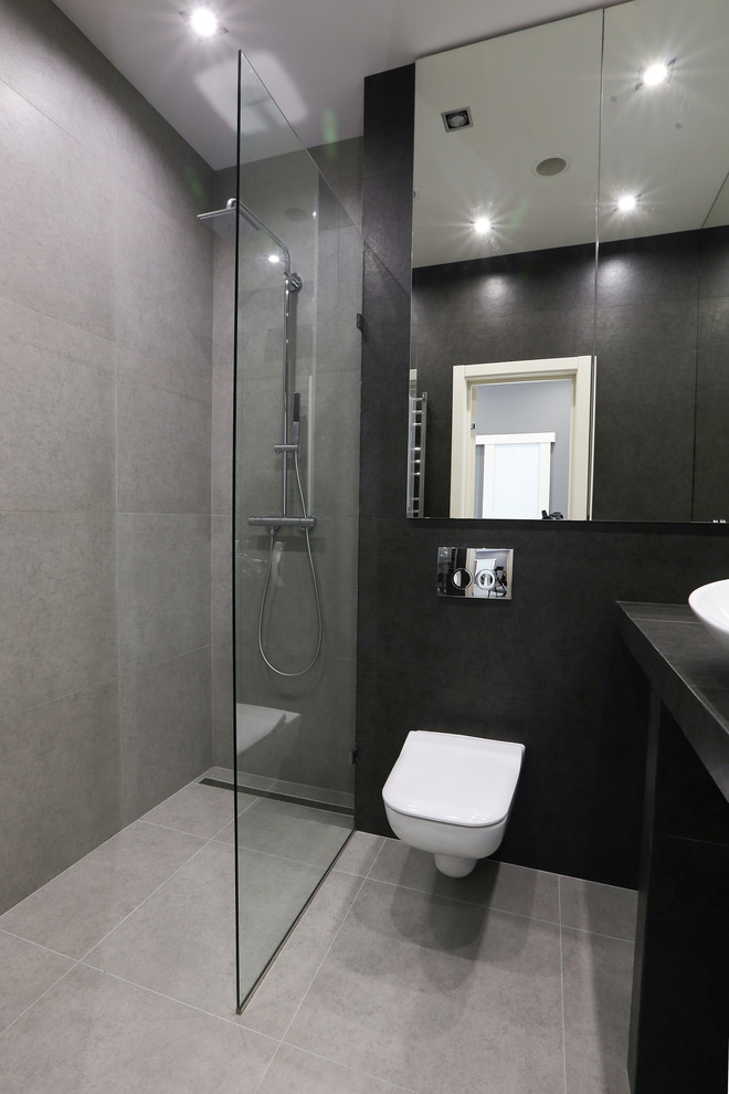 Ispirazione per una stanza da bagno minimal con doccia a filo pavimento, WC sospeso, piastrelle grigie e piastrelle nere