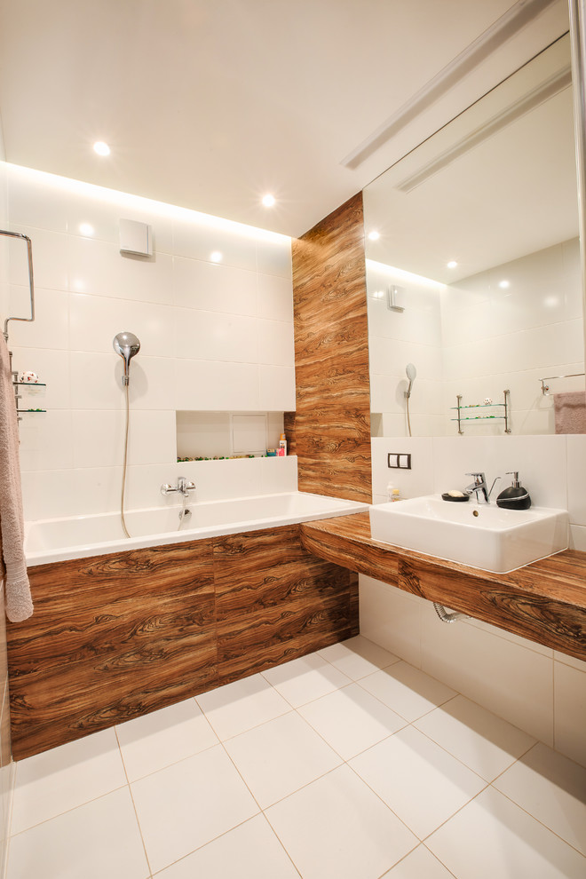 Idéer för att renovera ett funkis brun brunt badrum, med ett badkar i en alkov, en dusch/badkar-kombination, vita väggar, vit kakel, keramikplattor, klinkergolv i keramik, träbänkskiva och ett fristående handfat