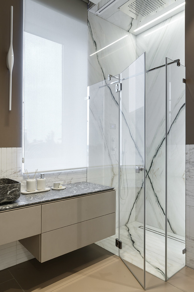 Modern inredning av ett grå grått badrum med dusch, med marmorkakel, marmorbänkskiva, bruna väggar, släta luckor, en kantlös dusch, svart och vit kakel, ett fristående handfat, dusch med gångjärnsdörr, bruna skåp och brunt golv