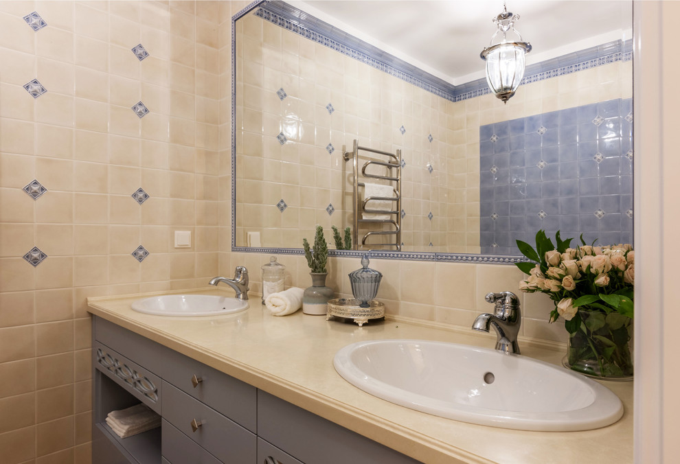 Immagine di una stanza da bagno chic con piastrelle blu, piastrelle beige e lavabo da incasso