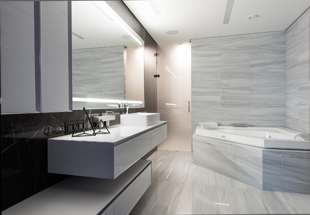 Diseño de cuarto de baño principal contemporáneo con armarios con paneles lisos, puertas de armario blancas, jacuzzi, baldosas y/o azulejos grises y lavabo sobreencimera