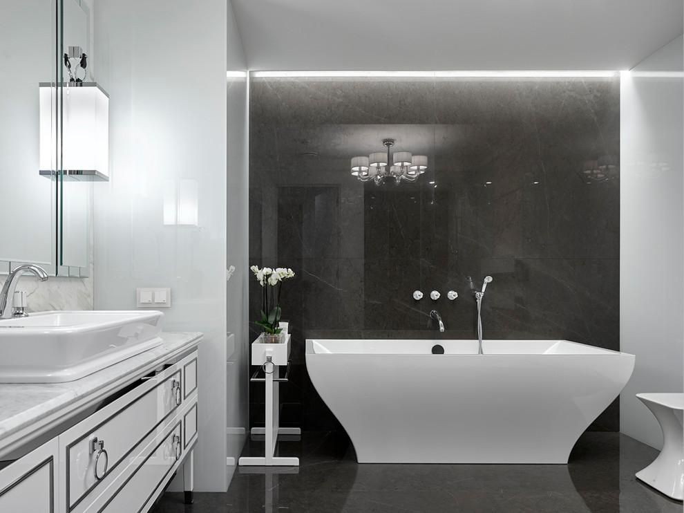 Foto de cuarto de baño principal actual con puertas de armario blancas, bañera exenta, paredes blancas, lavabo sobreencimera, suelo negro y encimeras blancas