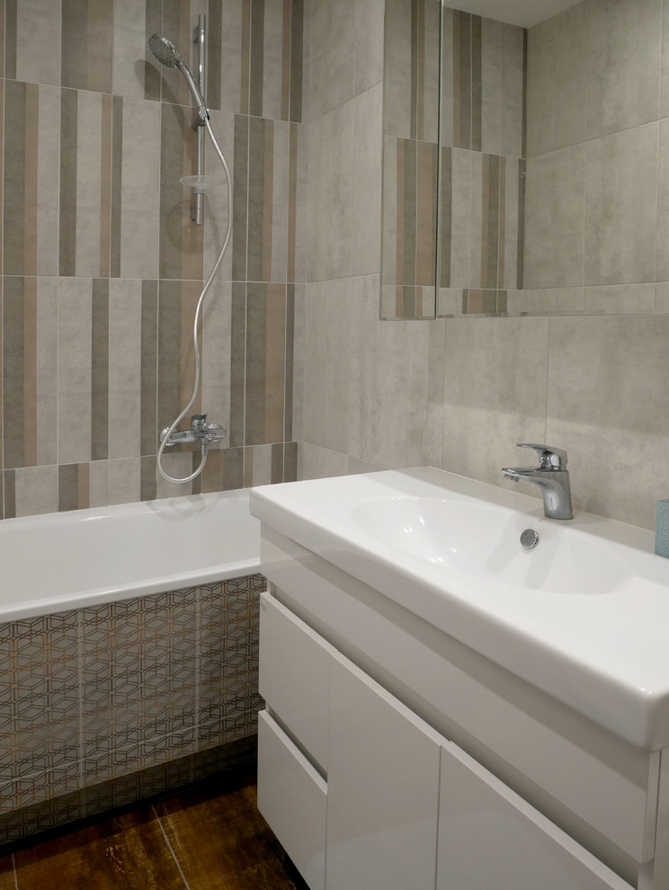 Photo of a small scandi ensuite bathroom in Moscow with flat-panel cabinets, white cabinets, a claw-foot bath, a shower/bath combination, a wall mounted toilet, grey tiles, porcelain tiles, grey walls, porcelain flooring, a built-in sink, solid surface worktops, brown floors, an open shower and white worktops.