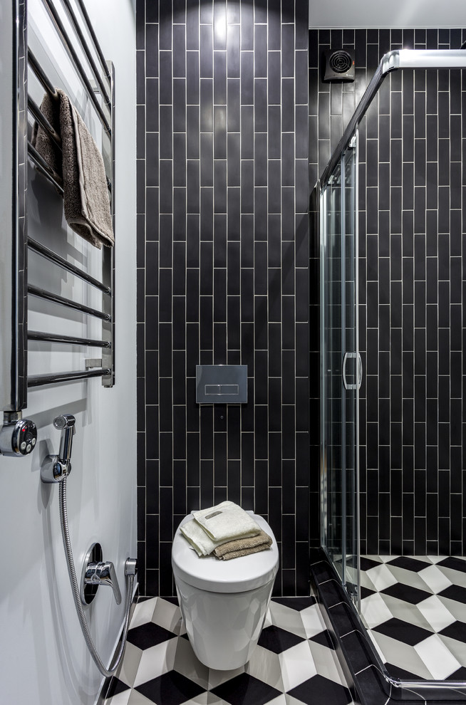 Minimalistisk inredning av ett litet badrum med dusch, med en hörndusch, en vägghängd toalettstol, keramikplattor, klinkergolv i keramik, flerfärgat golv, dusch med skjutdörr, vit kakel, svart kakel och vita väggar
