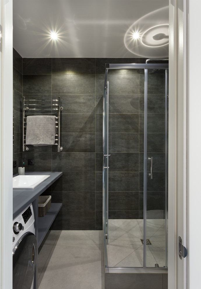 Inredning av ett industriellt litet badrum med dusch, med öppna hyllor, grå skåp, svart kakel, porslinskakel, klinkergolv i porslin, ett nedsänkt handfat, träbänkskiva, grått golv och dusch med skjutdörr