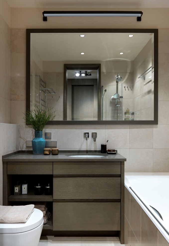 Cette photo montre une salle de bain principale tendance en bois brun de taille moyenne avec un placard à porte plane, un carrelage beige, un sol beige, une baignoire en alcôve, un combiné douche/baignoire, un lavabo encastré et un plan de toilette gris.