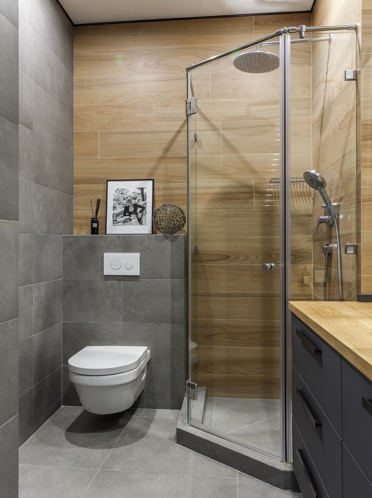 Свежая идея для дизайна: ванная комната в современном стиле с плоскими фасадами, серыми фасадами, угловым душем, инсталляцией, коричневой плиткой, серой плиткой, столешницей из дерева, серым полом, душем с распашными дверями и коричневой столешницей - отличное фото интерьера