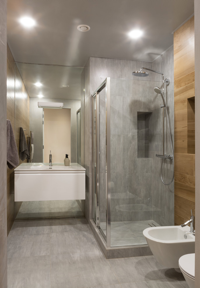 Свежая идея для дизайна: ванная комната в современном стиле с плоскими фасадами, белыми фасадами, угловым душем, биде, серой плиткой, душевой кабиной, монолитной раковиной и серым полом - отличное фото интерьера