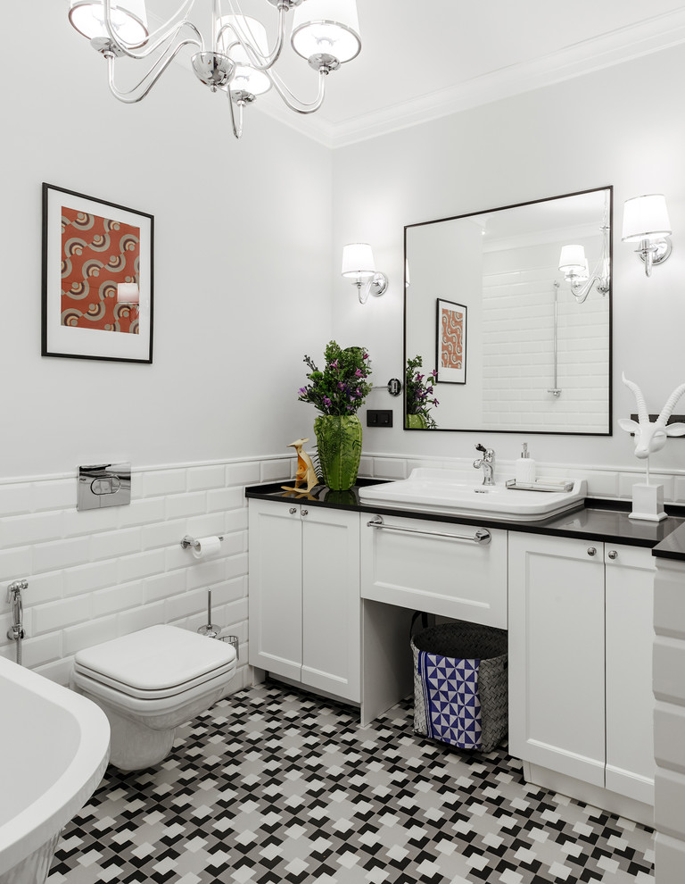 Example of a mid-sized transitional white tile and ceramic tile ceramic tile and multicolored floor bathroom design in Moscow with recessed-panel cabinets, white cabinets, a wall-mount toilet, gray walls, a drop-in sink, solid surface countertops and black countertops
