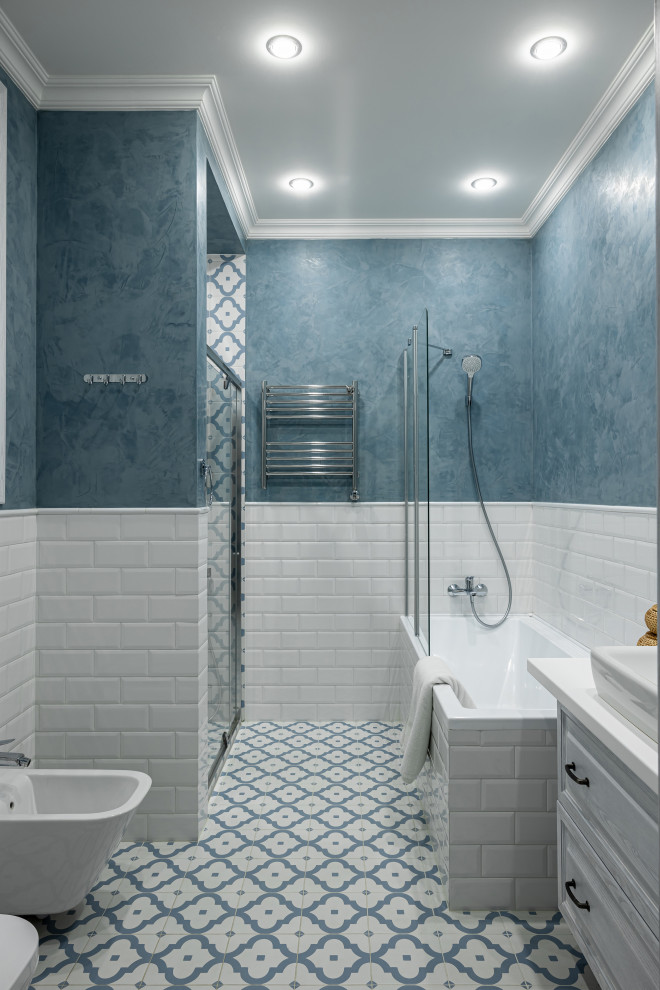 Стильный дизайн: ванная комната в стиле неоклассика (современная классика) с фасадами с выступающей филенкой, белыми фасадами, полновстраиваемой ванной, биде, белой плиткой, синими стенами, полом из керамогранита, белой столешницей и тумбой под одну раковину - последний тренд