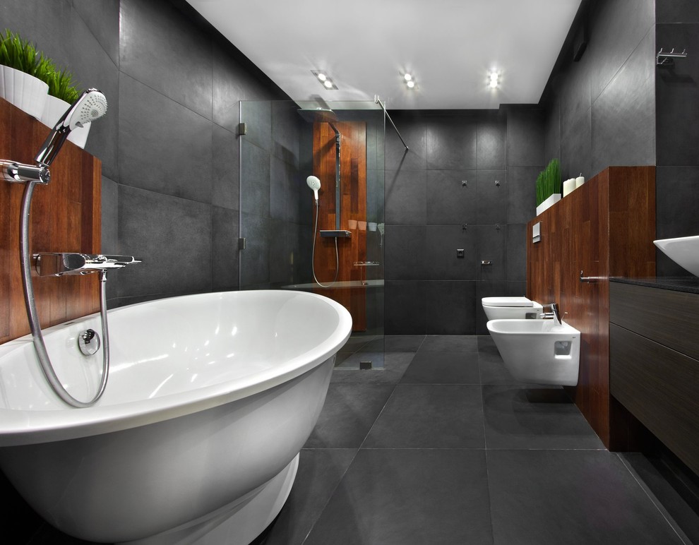 На фото: главная ванная комната в современном стиле с плоскими фасадами, темными деревянными фасадами, отдельно стоящей ванной, душем без бортиков, биде, серой плиткой, настольной раковиной, серым полом и открытым душем