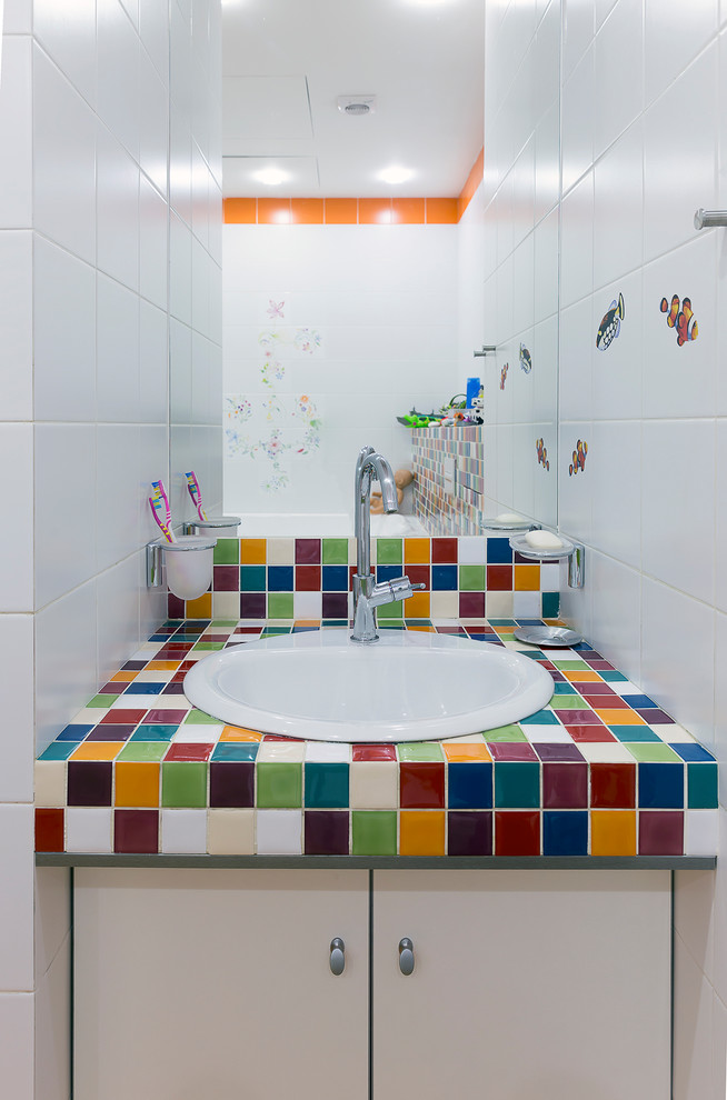 Стильный дизайн: детская ванная комната среднего размера в современном стиле с плоскими фасадами, бежевыми фасадами, полновстраиваемой ванной, раздельным унитазом, разноцветной плиткой, белыми стенами, полом из керамической плитки, врезной раковиной, столешницей из плитки, оранжевым полом и керамической плиткой - последний тренд