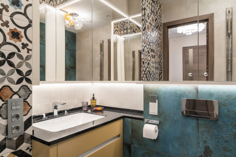 Пример оригинального дизайна: ванная комната в современном стиле с плоскими фасадами, желтыми фасадами, синей плиткой, врезной раковиной, черной столешницей и тумбой под одну раковину