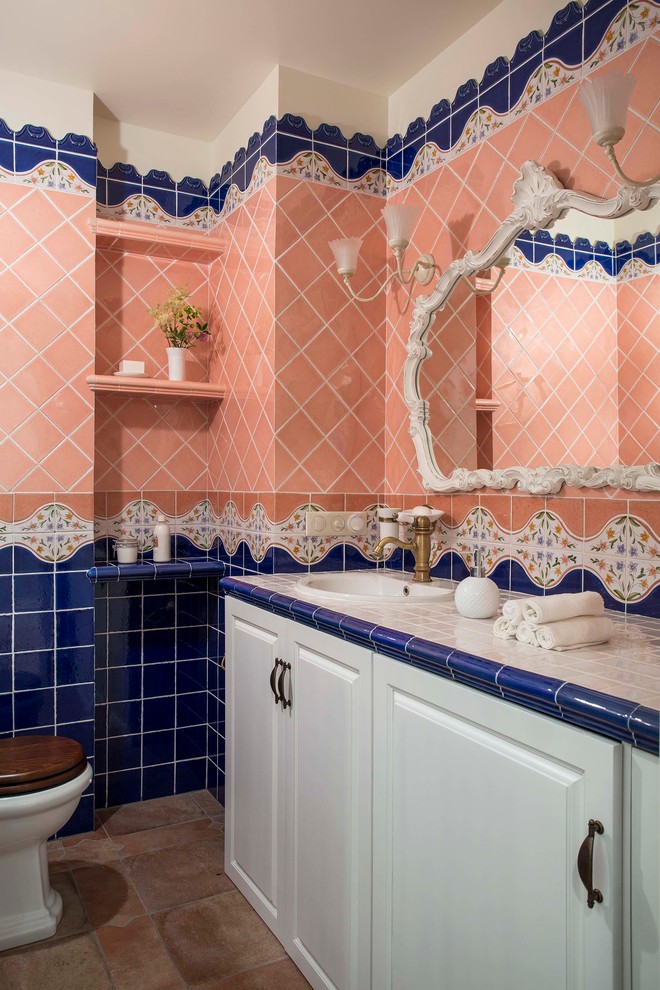 モスクワにあるトラディショナルスタイルのおしゃれな浴室 (レイズドパネル扉のキャビネット、白いキャビネット、青いタイル、ピンクのタイル、オーバーカウンターシンク、タイルの洗面台) の写真