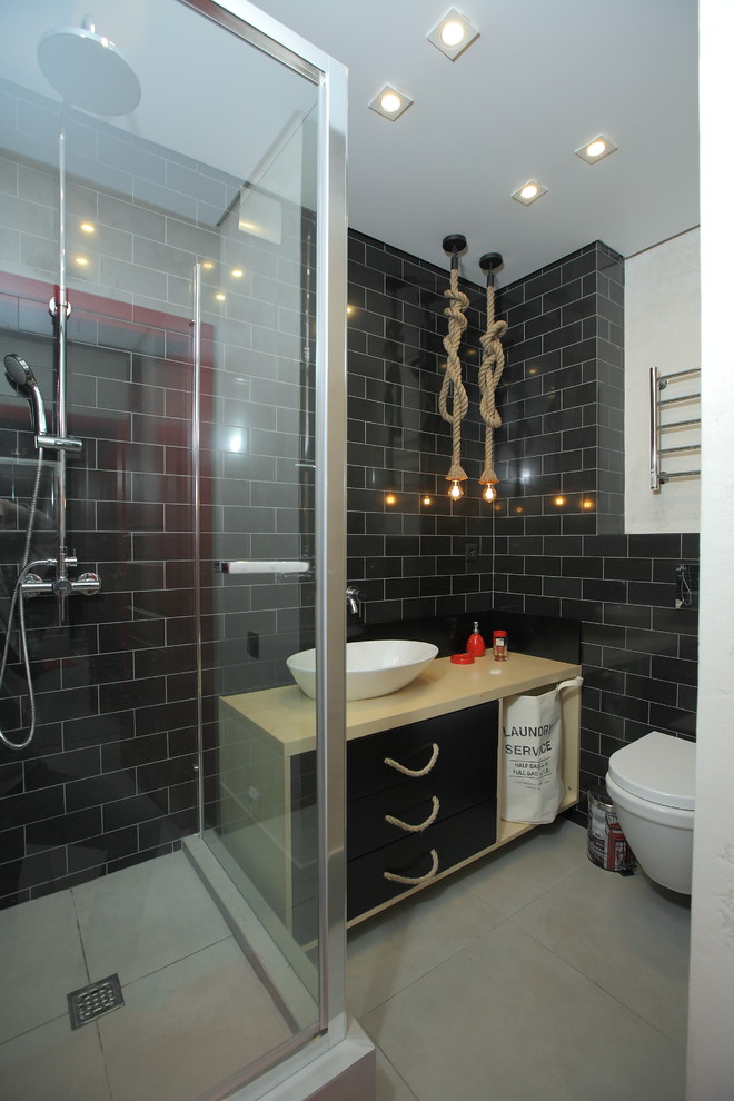 Inspiration for a contemporary shower room bathroom in Other with flat-panel cabinets, a wall mounted toilet, black tiles, porcelain flooring, a vessel sink, black cabinets, a corner shower, metro tiles and black walls.