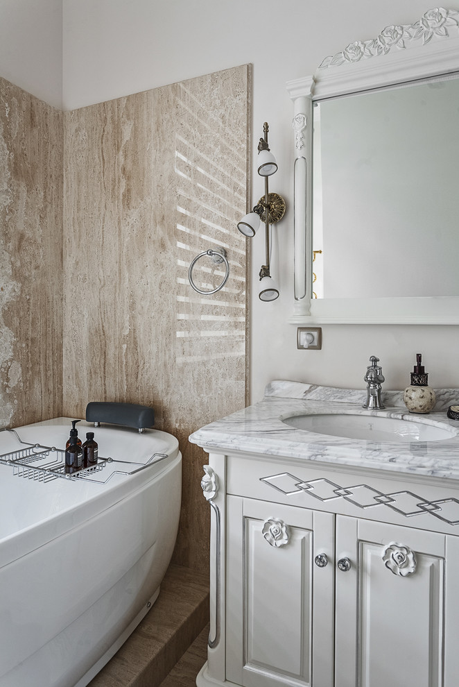 Стильный дизайн: большая главная ванная комната в стиле неоклассика (современная классика) с белыми фасадами, бежевой плиткой, белыми стенами и врезной раковиной - последний тренд