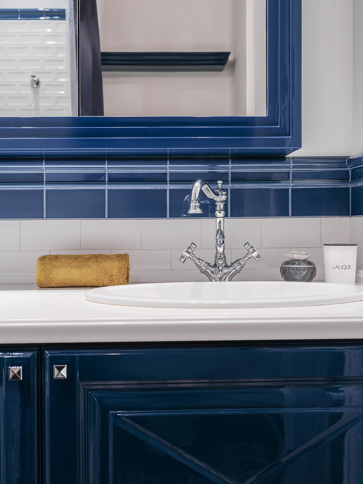Example of a mid-sized transitional white tile and ceramic tile bathroom design in Moscow with blue cabinets, white walls, a drop-in sink, solid surface countertops and raised-panel cabinets