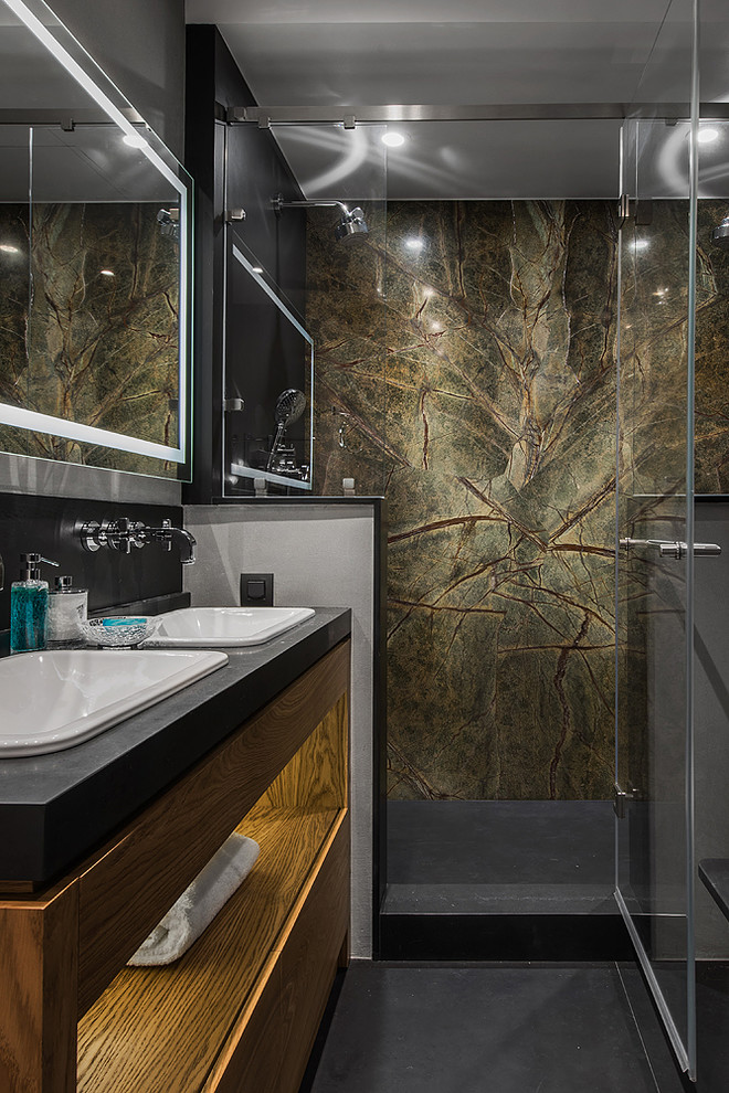 Пример оригинального дизайна: ванная комната в современном стиле с плоскими фасадами, фасадами цвета дерева среднего тона, душем в нише, душевой кабиной, накладной раковиной, черным полом, душем с распашными дверями и черной столешницей