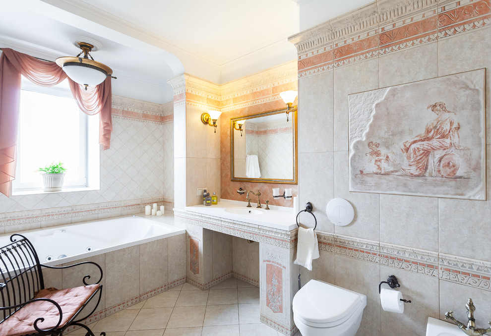 Aménagement d'une salle de bain principale méditerranéenne avec un bain bouillonnant, WC suspendus, un carrelage gris et un lavabo intégré.