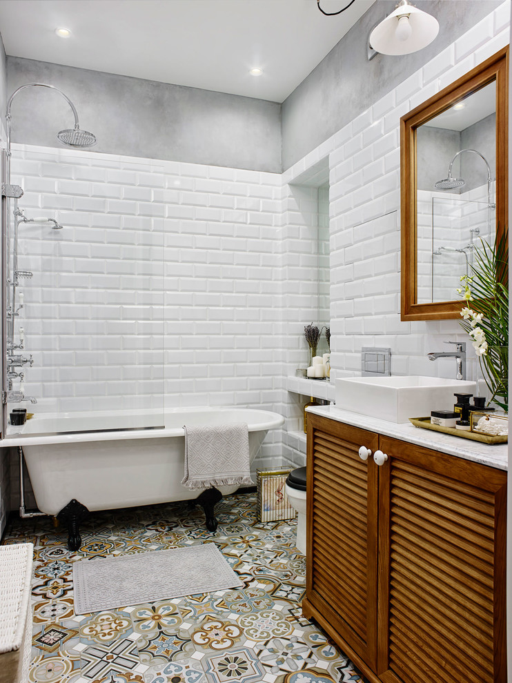 Свежая идея для дизайна: главная ванная комната в стиле фьюжн с фасадами с филенкой типа жалюзи, фасадами цвета дерева среднего тона, ванной на ножках, душем над ванной, раздельным унитазом, белой плиткой, разноцветной плиткой, плиткой кабанчик, серыми стенами, настольной раковиной и открытым душем - отличное фото интерьера