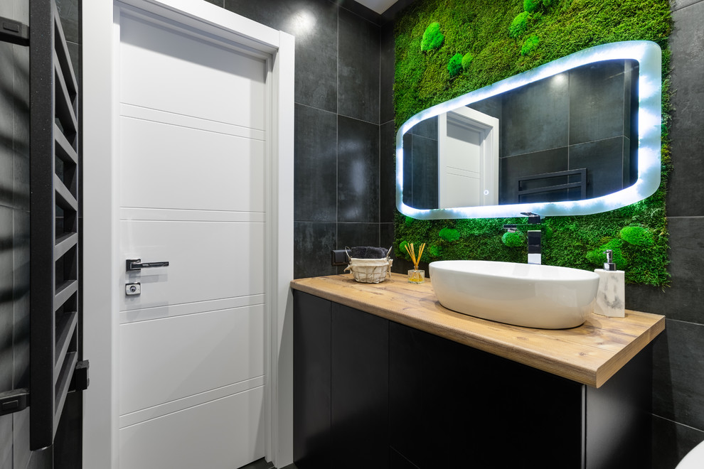 Design ideas for a contemporary bathroom in Saint Petersburg with flat-panel cabinets, black cabinets, black tiles, a vessel sink, wooden worktops and brown worktops.