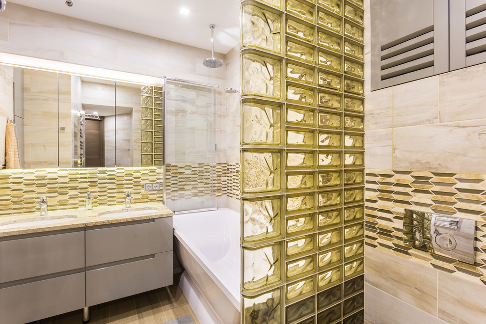 Стильный дизайн: главная ванная комната в современном стиле с плоскими фасадами, серыми фасадами, ванной в нише, душем над ванной, бежевой плиткой и врезной раковиной - последний тренд