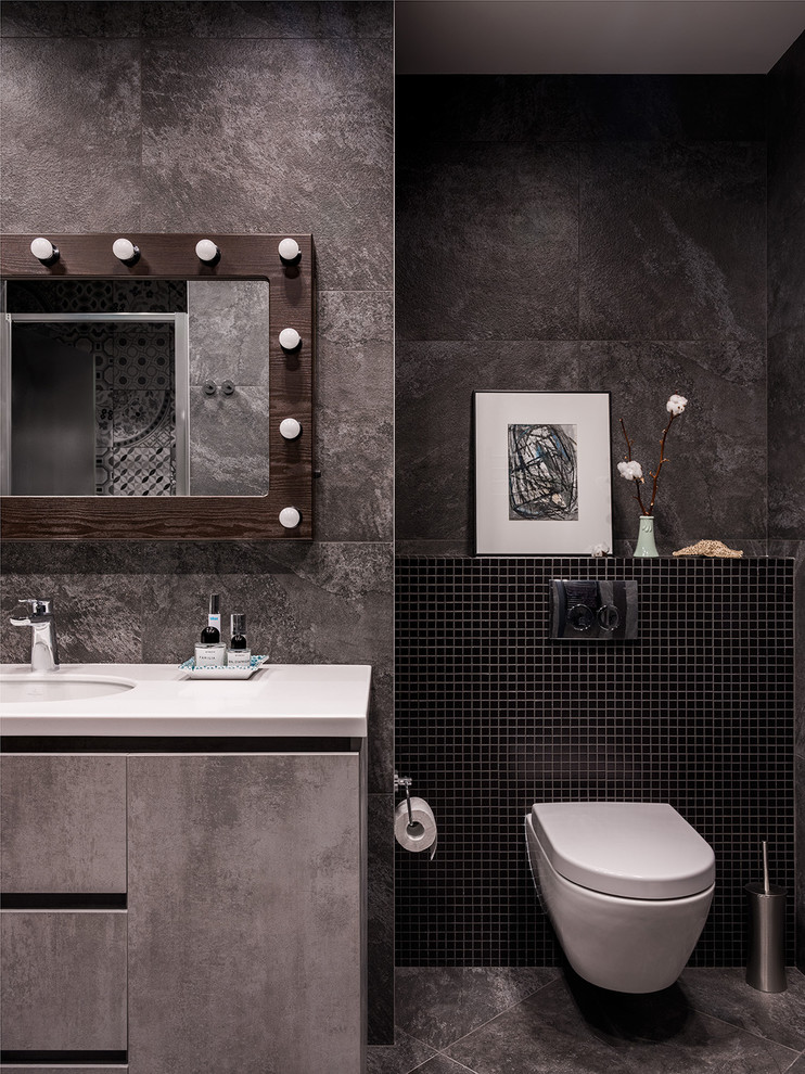 Aménagement d'une salle de bain contemporaine avec un placard à porte plane, des portes de placard grises, WC suspendus, un carrelage gris, un lavabo encastré et un sol gris.