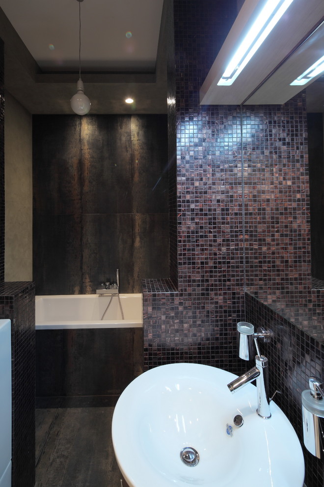Ispirazione per una piccola stanza da bagno industriale con vasca sottopiano, pareti multicolore, pavimento in gres porcellanato e pavimento nero