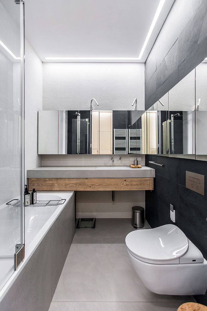 Idéer för funkis en-suite badrum, med släta luckor, skåp i mellenmörkt trä, en dusch/badkar-kombination, en vägghängd toalettstol, svart kakel och vita väggar