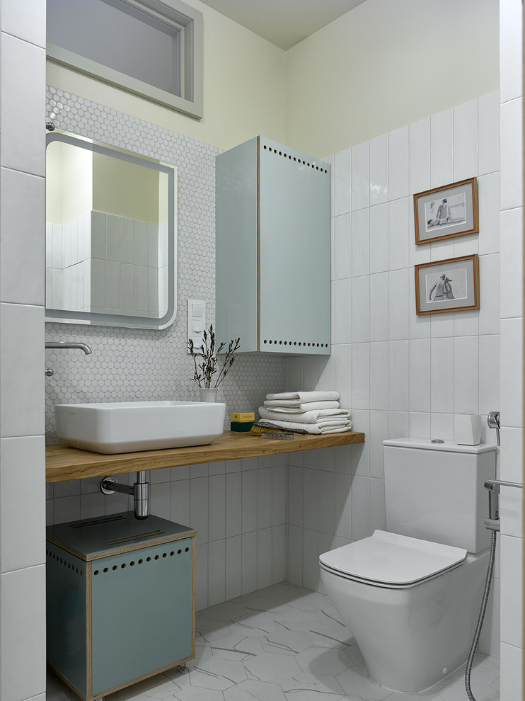 Idéer för att renovera ett funkis brun brunt badrum, med släta luckor, turkosa skåp, en toalettstol med separat cisternkåpa, vit kakel, mosaik, ett fristående handfat, träbänkskiva och vitt golv