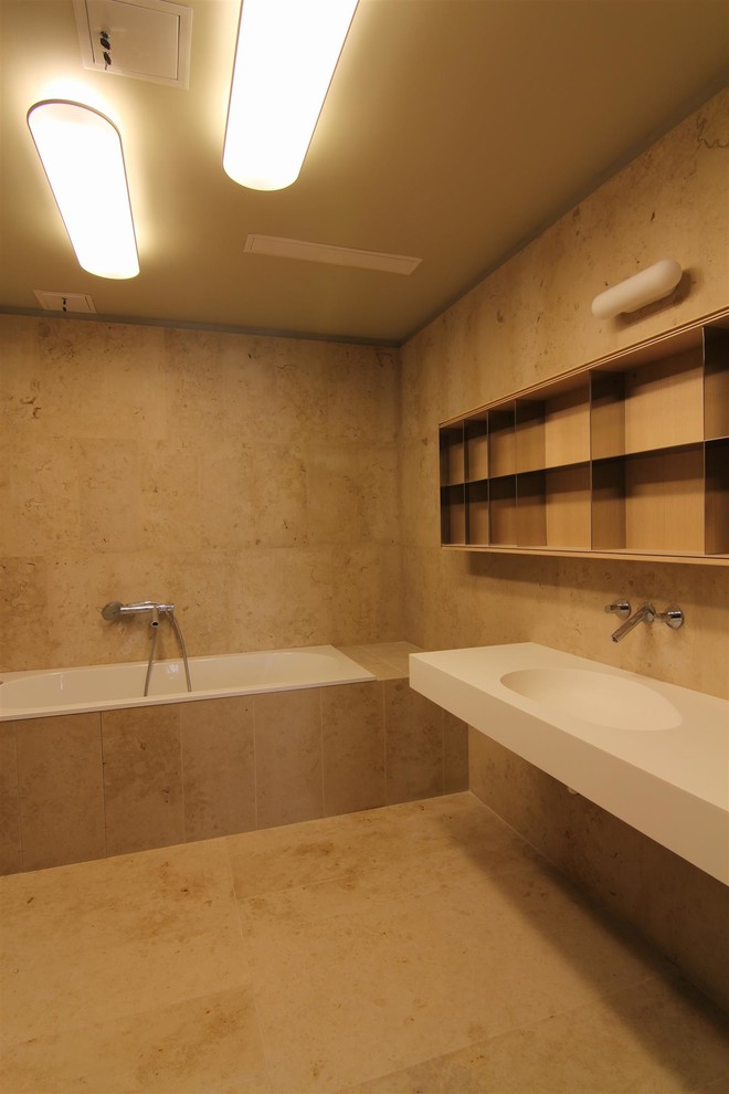 Источник вдохновения для домашнего уюта: главная ванная комната в современном стиле с полновстраиваемой ванной, бежевой плиткой, плиткой из листового камня, полом из известняка, консольной раковиной и бежевым полом